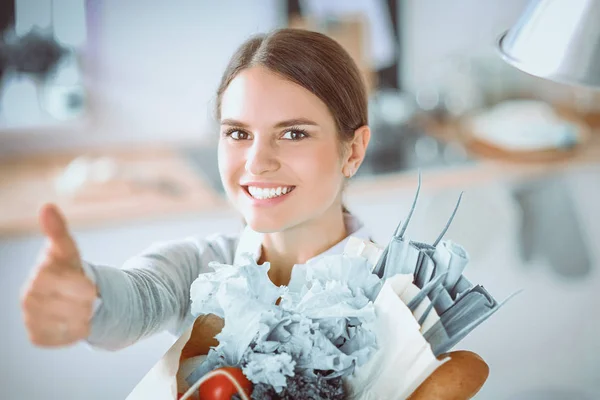 Jonge vrouw met boodschappentas met groenten.Staande in de keuken — Stockfoto