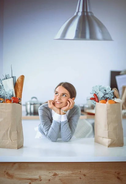 Smiling young woman in the kitchen near desk — Stock Photo, Image