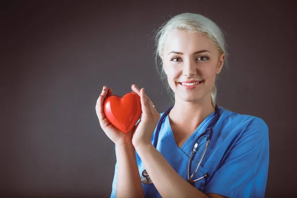 Young doctor woman with stethoscope holding heart — Stock Photo, Image