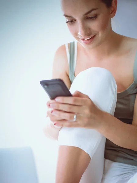 Aantrekkelijke Kaukasische meisje zittend op de vloer met telefoon — Stockfoto