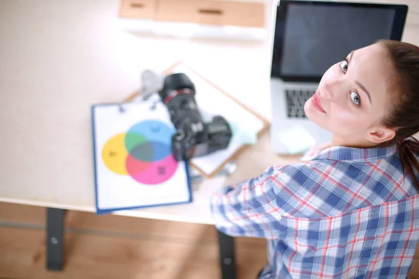 Kvinnlig fotograf sitter på skrivbordet med bärbar dator — Stockfoto