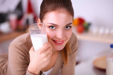 Gülümseyen çekici kadın mutfağın içinde kahvaltı yapıyor.