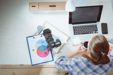 Masada dizüstü bilgisayarla oturan kadın fotoğrafçı.