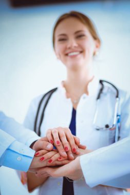 Doktorlar ve hemşireler tıbbi bir ekipte el ele tutuşuyorlar.