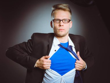 Genç işadamı hareket ve bir süper kahraman gibi gömleğini, yırtılma gri arka plan üzerinde izole