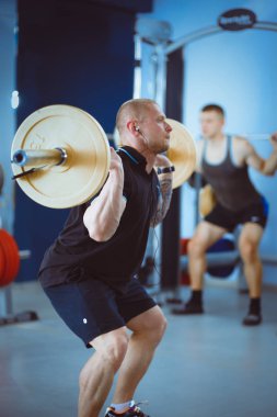 Genç adam eğitmen ile spor salonunda halter kaldırma