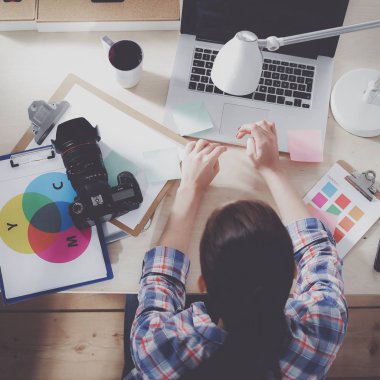Masada dizüstü bilgisayarla oturan kadın fotoğrafçı.
