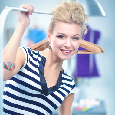 Raf ofiste askıları ile yakınındaki güzel genç stilist