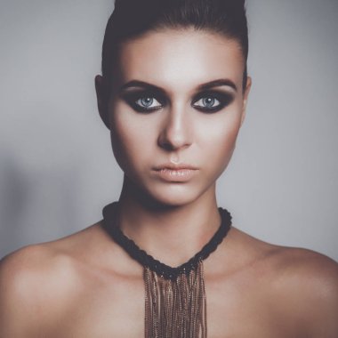 Gri arka plan üzerinde duran güzel genç kadın