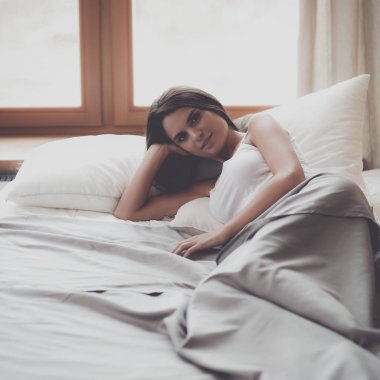 Evdeki yatakta uzanmış güzel esmer