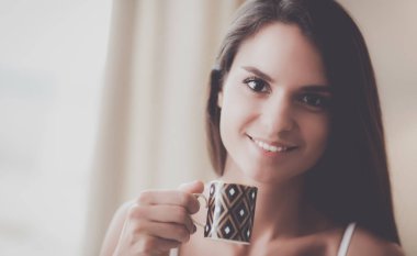 bir bardak süt ile yatakta oturan genç kadın