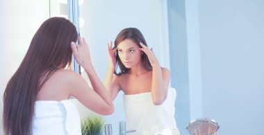 Çekici genç bir kadın yüzüne krem sürüyor.