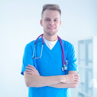 Steteskoplu doktor ayakta, çapraz kollu, beyaz arka planda izole.