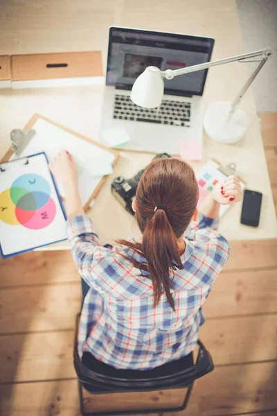 Vrouwelijke fotograaf zittend op het bureau met laptop — Stockfoto