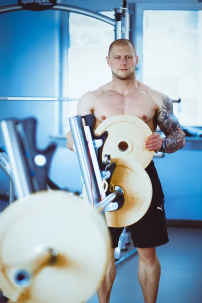 Joven levantando la barra en el gimnasio con instructor — Foto de Stock