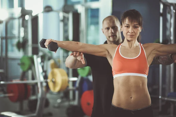 Schöne Frau im Fitnessstudio beim Training mit ihrem Trainer — Stockfoto