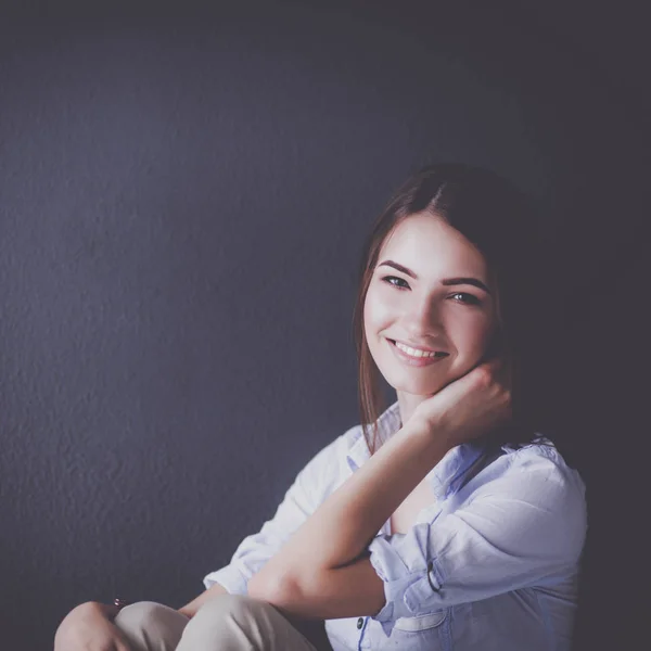 Mujer joven sentada en el suelo cerca de la pared oscura — Foto de Stock