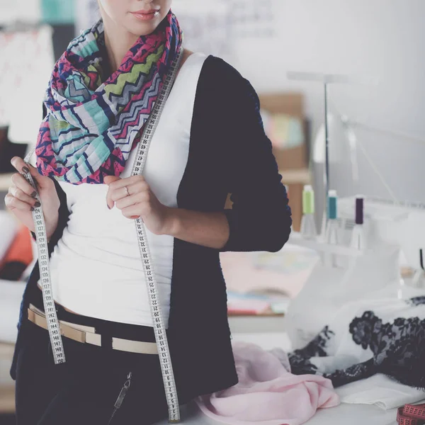 Beautiful fashion designer standing near desk in studio — Stock Photo, Image