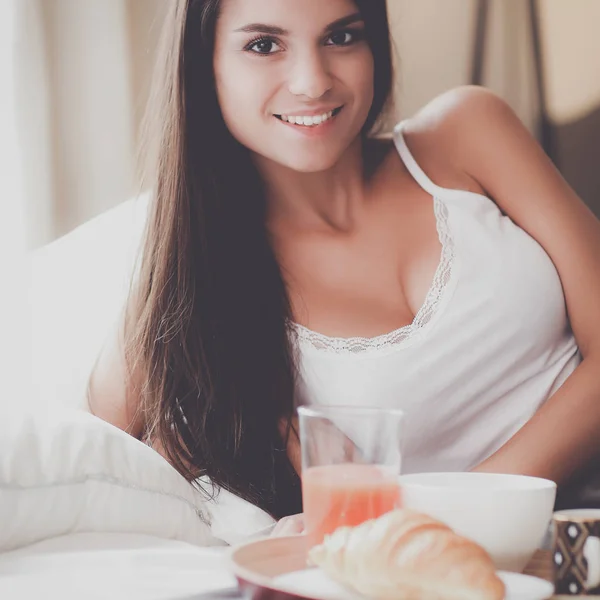 Ung kvinna sitter i sängen med en kopp mjölk — Stockfoto