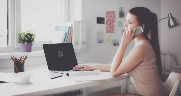 Jovem empresária sentada na mesa e conversando ao telefone — Fotografia de Stock