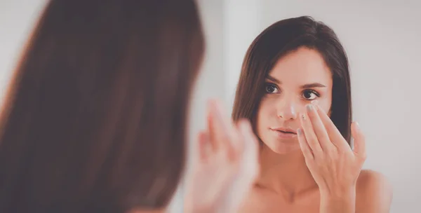 Attraktive junge Frau cremt ihr Gesicht ein — Stockfoto