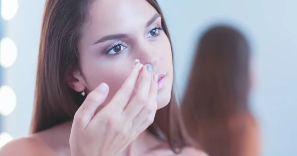 Atractiva joven que aplica crema en su cara — Foto de Stock
