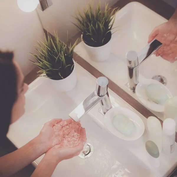 Junge Frau wäscht sich im Badezimmer ihr Gesicht mit sauberem Wasser — Stockfoto