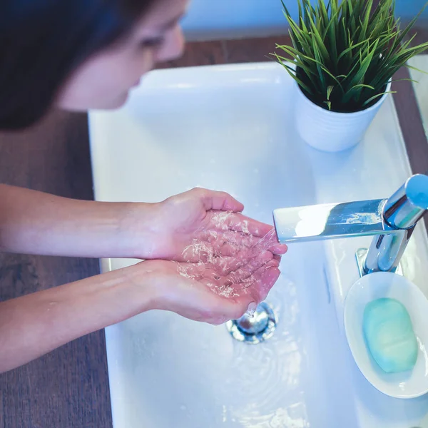 Giovane donna che si lava il viso con acqua pulita in bagno — Foto Stock