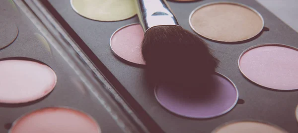 Pinceles de maquillaje y sombras de maquillaje en el escritorio —  Fotos de Stock