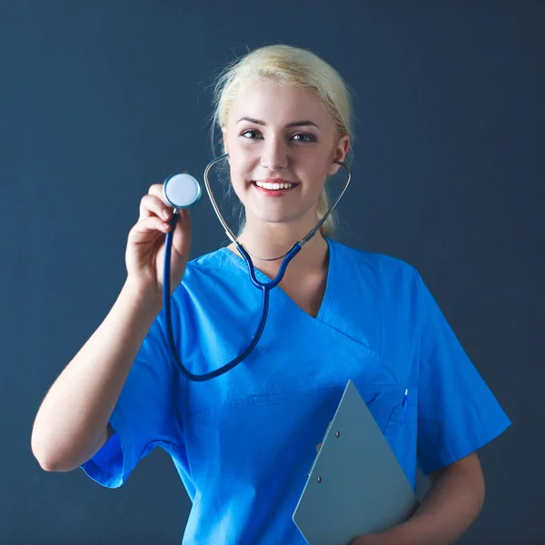 Steteskopla dinleyen kadın doktor, gri arka planda izole edilmiş. — Stok fotoğraf