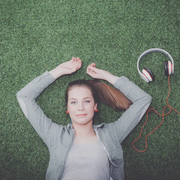 Relaxed woman listening to the music with headphones lying on grass — Stock Photo, Image