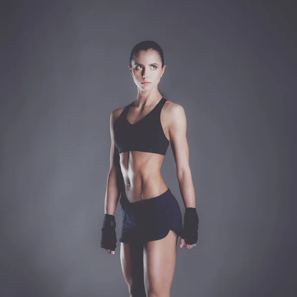 Muscular young woman posing in sportswear against black background — Stock Photo, Image