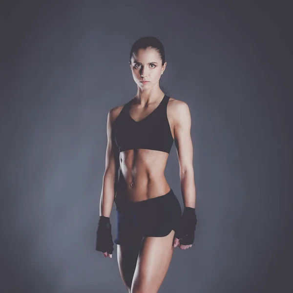 Muscular young woman posing in sportswear against black background — Stock Photo, Image