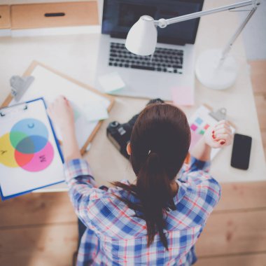 Masada dizüstü bilgisayarla oturan kadın fotoğrafçı.