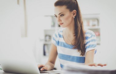 Elinde evrakları olan kadın masanın üstünde oturuyor.