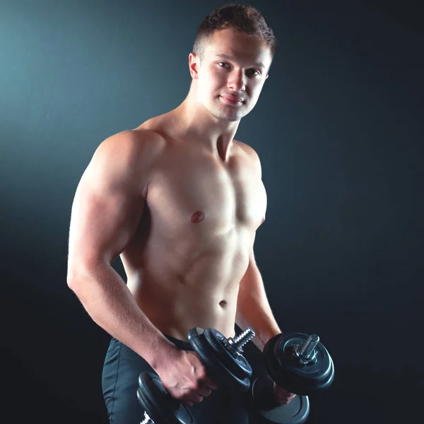 Красивый мускулистый мужчина работает с гантелями — стоковое фото