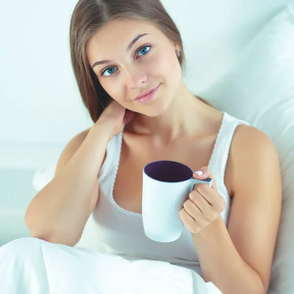 Hezká mladá žena v posteli těší šálek čaje — Stock fotografie