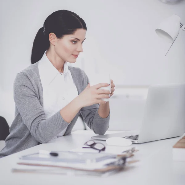Молода бізнес-леді сидить на столі з чашкою в офісі — стокове фото