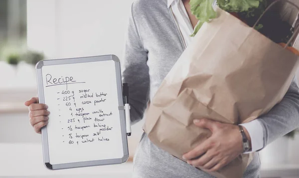 Jeune femme tenant un sac d'épicerie avec des légumes Debout dans la cuisine — Photo