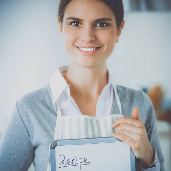 Kvinna i köket hemma, stående nära skrivbord med mapp — Stockfoto