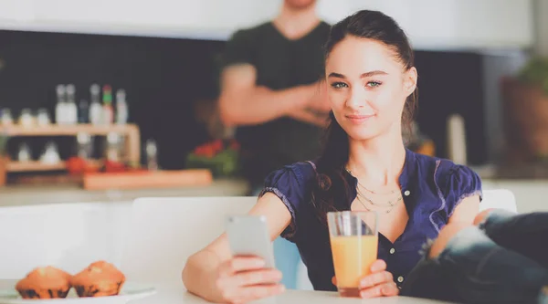 Lyckliga par med smartphone som sitter i köket — Stockfoto