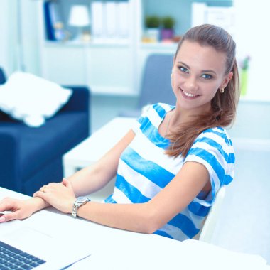 Elinde evrakları olan kadın masanın üstünde oturuyor.