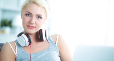 Evdeki genç ve güzel kadın kanepede oturup müzik dinliyor.