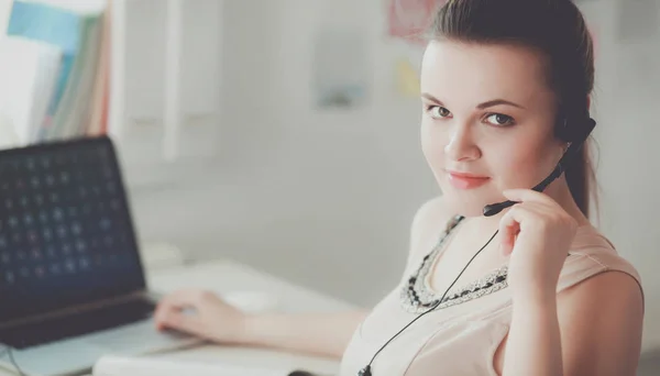 Porträtt av vacker affärskvinna som arbetar vid sitt skrivbord med headset och laptop — Stockfoto