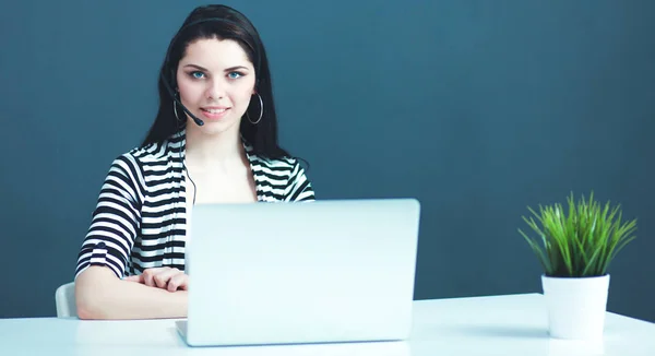 Schöne Geschäftsfrau am Schreibtisch mit Headset und Laptop — Stockfoto