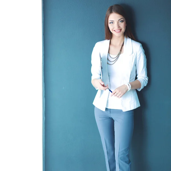 Young woman holding a laptop, standing on gray background — Stock Photo, Image