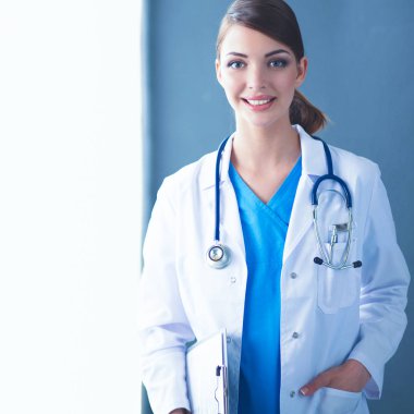 Gri arka planda, dosyasına ve steteskopuna sahip genç doktor ya da doktor.