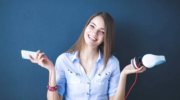 Menina sorridente com fones de ouvido sentado no chão perto da parede — Fotografia de Stock