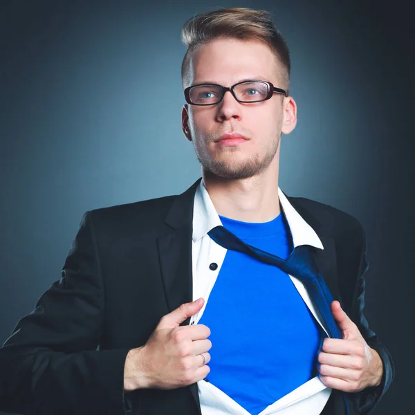 Young businessman acting like a super hero and tearing his shirt, isolated on gray background — Stock Photo, Image