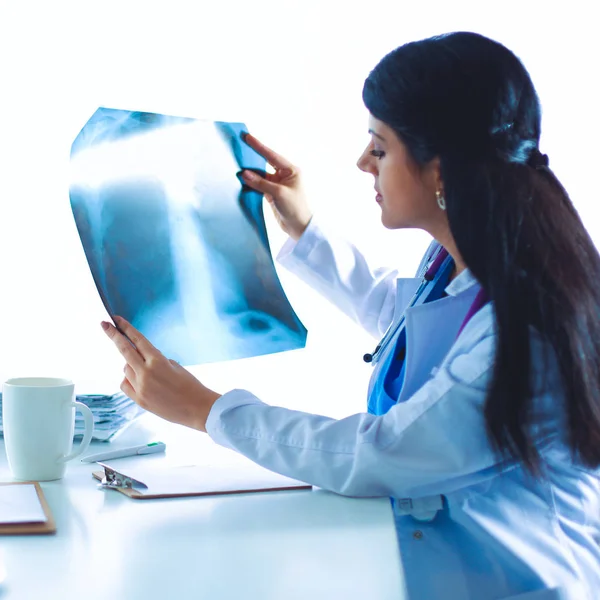 Jovem médica estudando imagem de raios-x, sentada na mesa — Fotografia de Stock